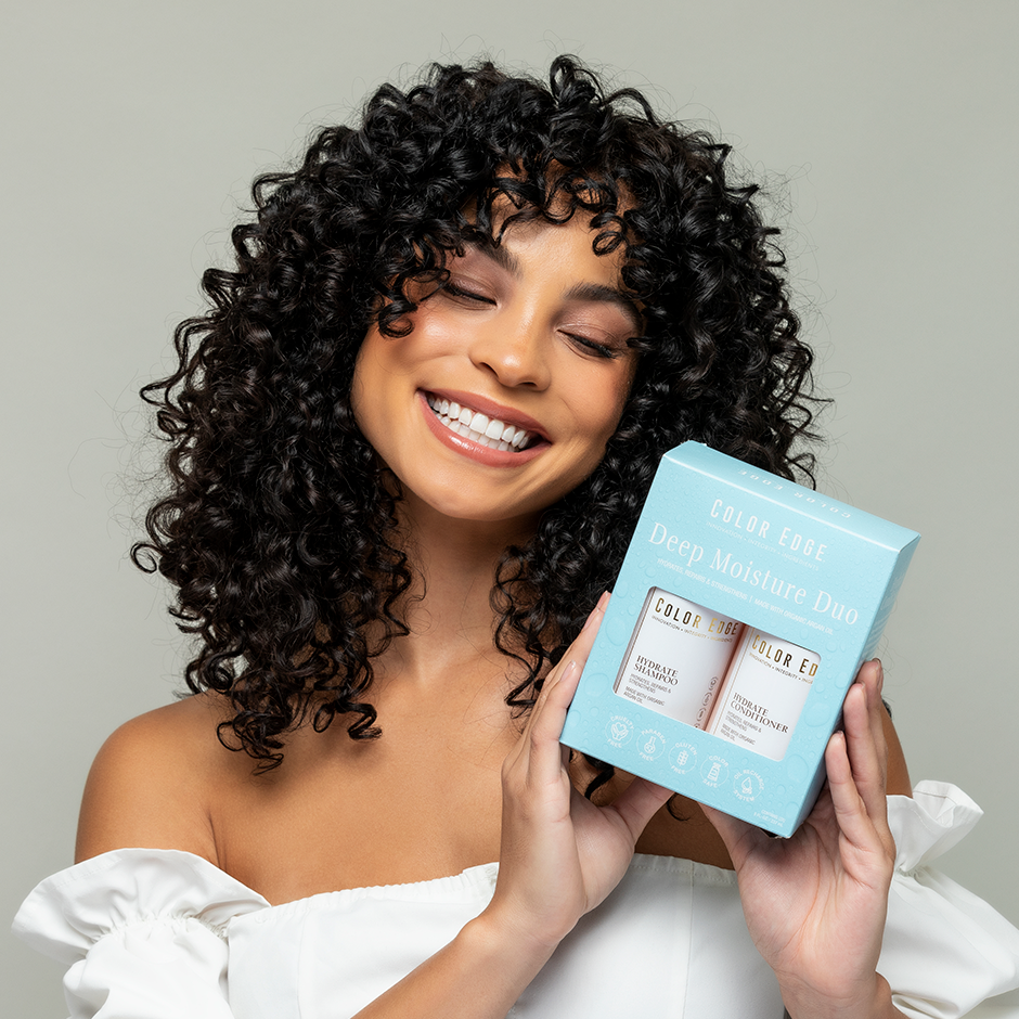 Woman with curly hair holding up Deep Moisture Duo bundle