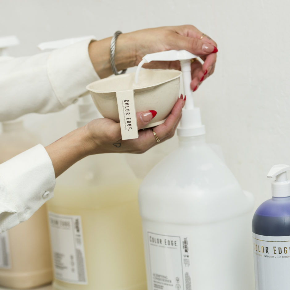 Stylist pumping out product from gallon size using the pump