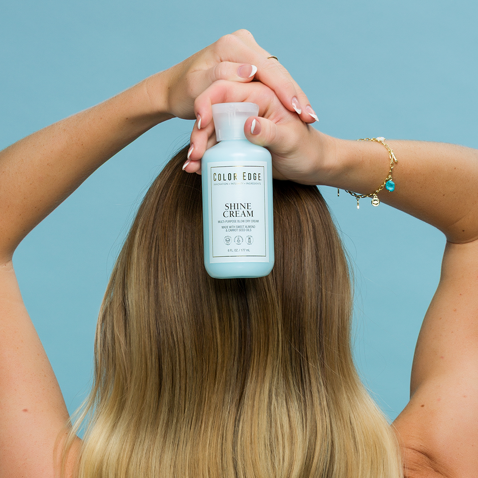 Woman holding bottle of Shine Cream behind her shiny hair