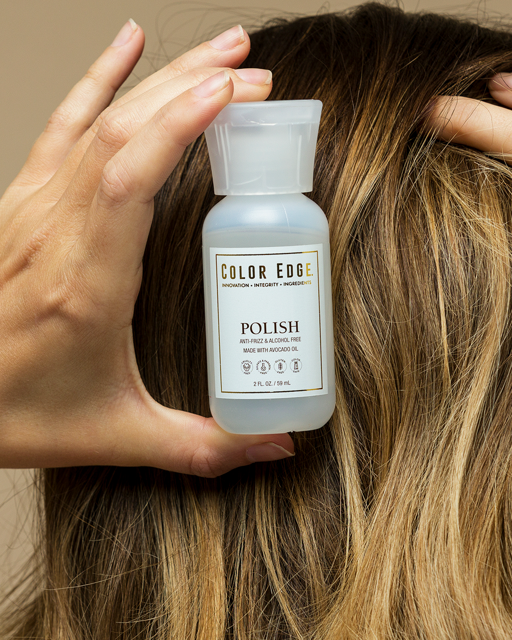Person holding a bottle of Color Edge Polish against their hair