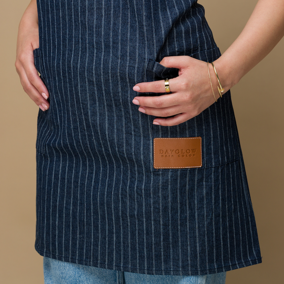 Blue denim pinstriped apron. Closeup details of the leather logo patch